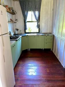a kitchen with green cabinets and a window at Casa Centenária com 20 min de Gramado in Três Coroas