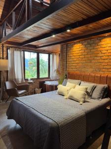 a bedroom with a large bed and a brick wall at Casa da Pedra Serrinha in Resende +134 photos