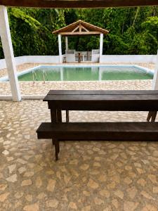a wooden bench sitting in front of a swimming pool at Casa da Pedra Serrinha in Resende