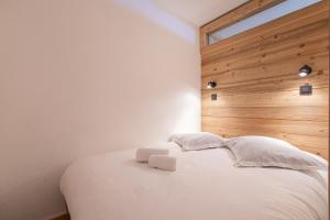 a bedroom with a white bed with a wooden wall at Résidence Hôtel Rent - Megève in Megève