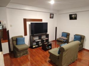 a living room with two chairs and a flat screen tv at Cusco Tahuanwasi Apartments in Cusco