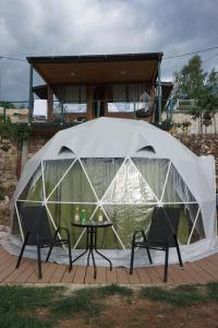 a tent with two chairs and a table in front of a house at Glamping Krupac Lake in Blaca