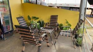 three chairs and a table in front of a yellow wall at Pousada recanto da fronteira in Oiapoque