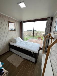 a bedroom with a bed and a large window at Casa del Sol in Cobquecura