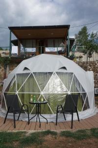 a tent with a table and chairs in front of a house at Glamping Krupac Lake in Blaca