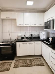 a kitchen with white cabinets and black appliances at Apollos Garden in Belém