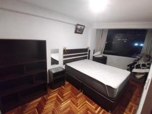 a bedroom with a bed and a flat screen tv at Cusco Tahuanwasi Apartments in Cusco