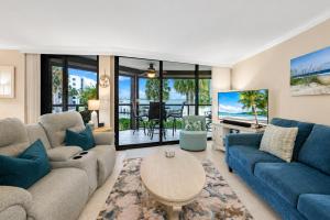a living room with blue couches and a tv at Waterfront Island Oasis! Heated Pool with Stunning View & 2 Full Bath in Marco Island