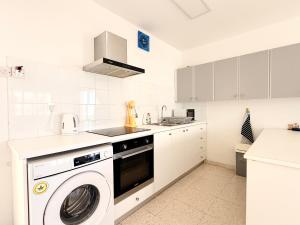 a white kitchen with a washing machine in it at Cozy holyday apartament in Paralimni
