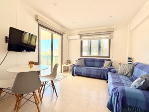 a living room with a blue couch and a table at Cozy holyday apartament in Paralimni