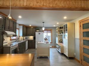 a kitchen with wooden cabinets and a white refrigerator at La maison du petit rang in Saint-Éloi