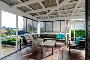 a screened in porch with a couch and chairs at 19 Broadway in Martinborough +25 photos