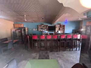 a bar with red bar stools in a room at Sumanya guest house 6 in Sukuta