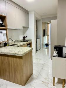 a kitchen with white cabinets and a marble floor at Apto novo prox Parque Thermal e centro de evento in Piratuba