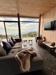 a living room with a couch and a flat screen tv at Gran Casa con Vista Increíble, Tinaja y WiFi in Cobquecura