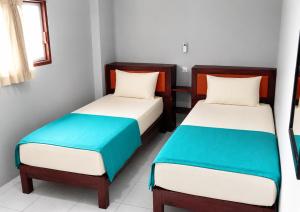 two beds in a room with white and blue at Tanjung Inn in Wonosari +2 photos