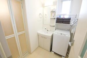 a white bathroom with a sink and a washing machine at Green Gables B棟 108 in Toyama