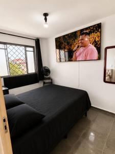 a bedroom with a black bed and a picture on the wall at Apartamento Residencial Alice in Uberaba