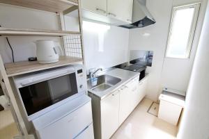 a small kitchen with a sink and a microwave at Green Gables A棟 105 in Toyama