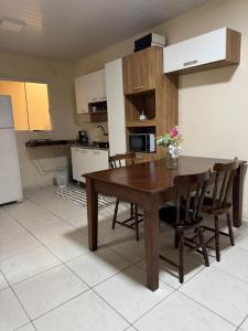a kitchen with a wooden table and some chairs at Saif Economy Apart in Paranaguá