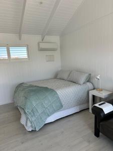 a white bedroom with a bed and a table at Luxury Poolside Studio Near Hobbiton in Matamata +14 photos