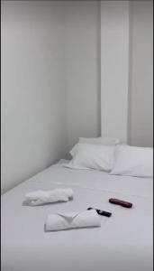a white bed with a remote control and towels on it at Hotel Azulado - Como el mar in Jamundí