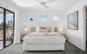 a white bedroom with a large bed and a window at Oasis By Khove - Broadbeach Waters in Gold Coast
