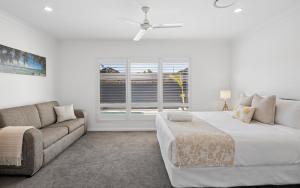 a bedroom with a bed and a couch and a window at Oasis By Khove - Broadbeach Waters in Gold Coast