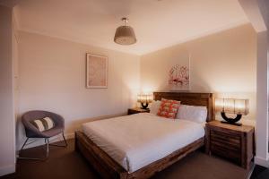 a bedroom with a large bed and a chair at Ruby SoHo Workshop Villa in Port Sorell