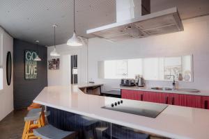 a kitchen with a white counter top and red cabinets at Ruby SoHo Workshop Villa in Port Sorell