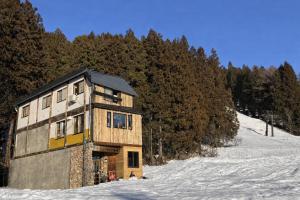 a building on a snow covered hill with trees at Koguma no ie in Nozawa Onsen