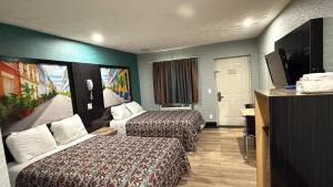 a hotel room with two beds and a flat screen tv at Midway Motel in Patchogue