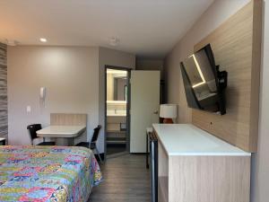 a hotel room with a bed and a desk with a television at Midway Motel in Patchogue