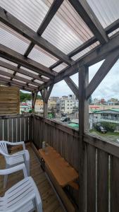 a wooden deck with two white chairs and a table at 奄美ザナゼステイTheNazeStay in Amami
