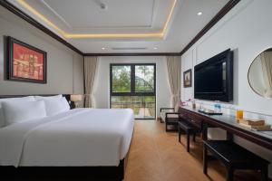 a bedroom with a large white bed and a desk at Aluna Tam Coc Hotel in Ninh Binh
