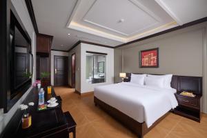a bedroom with a large white bed and a television at Aluna Tam Coc Hotel in Ninh Binh