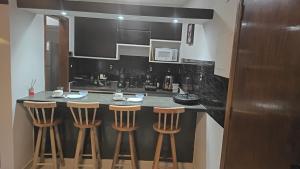 a kitchen with a counter with stools in it at Flat São Vicente Praia Piscina Garagem in São Vicente