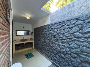 a bathroom with a stone wall and a sink at Coco Garden Pool Villas in Kubutambahan