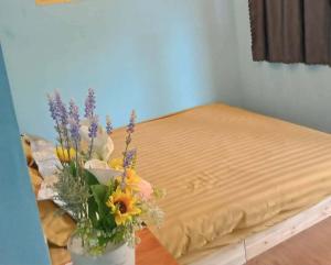 a vase of flowers on a table next to a bed at BONNIE HOMESTAY Mui Ne in Mui Ne +145 photos