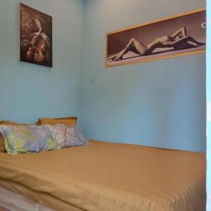 a bed in a room with two pictures on the wall at BONNIE HOMESTAY Mui Ne in Mui Ne