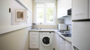 a kitchen with a washing machine and a sink at Hondarribia con Piscinas, Terraza Privada, Parking y Tenis - CASA OLABIDE in Hondarribia
