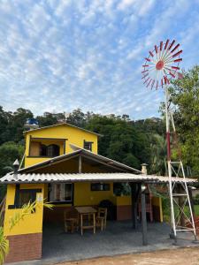 a yellow house with a windmill in front of it at Catavento in Paty do Alferes