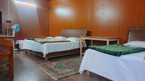 a room with two beds and a rug at trigun pahadi hub in Uttarkāshi