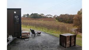 a patio with a table and a chair in front of a field at Churinga Orchards by Tiny Away in Lenswood