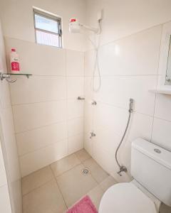 a white bathroom with a shower and a toilet at AmazHost - Casa Rosa com Split, Wi-Fi 700 Mb e Água Quente in Belém +2 photos