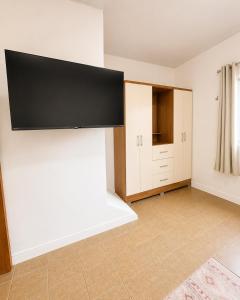 a living room with a flat screen tv on a wall at AmazHost - Casa Rosa com Split, Wi-Fi 700 Mb e Água Quente in Belém