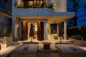 a patio with two tables and umbrellas in front of a building at Heritage Villas in Uluwatu