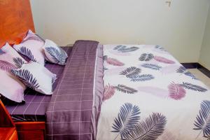 a bed with a purple comforter and pillows at Kasese Explorers Homestay in Kasese