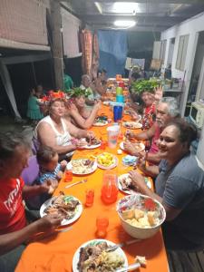 a group of people sitting at a long table eating food at TEMATAOAVEA Dortoir in Fare