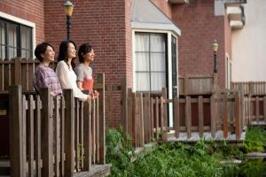 Drei Frauen stehen auf einem Zaun vor einem Haus in der Unterkunft Forest Villa Huis Ten Bosch in Sasebo